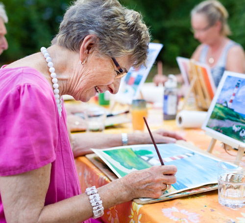 Woman painting as one of many social activities for seniors