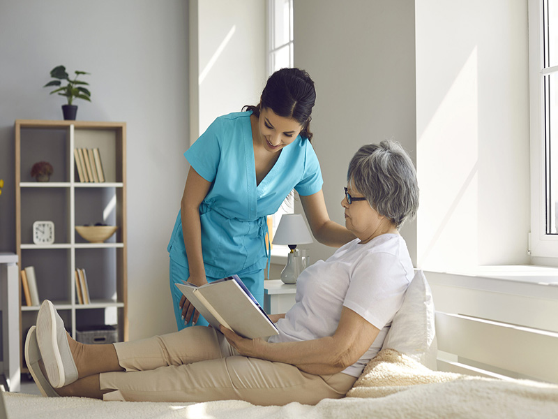 Elderly woman in bed being taken care of by a nurse