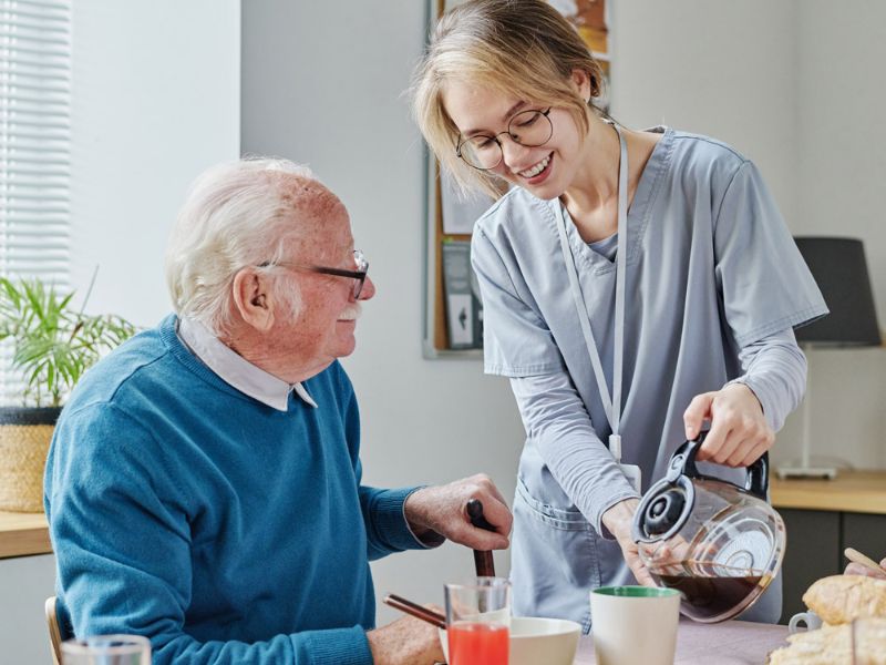 senior home caregiver pouring coffee for a post-hospitalized senior