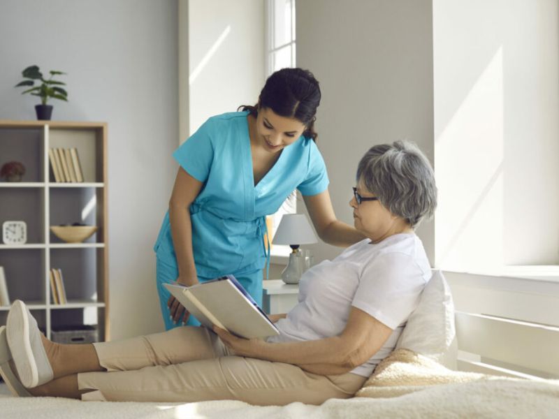 Elderly woman in bed being taken care of by a nurse