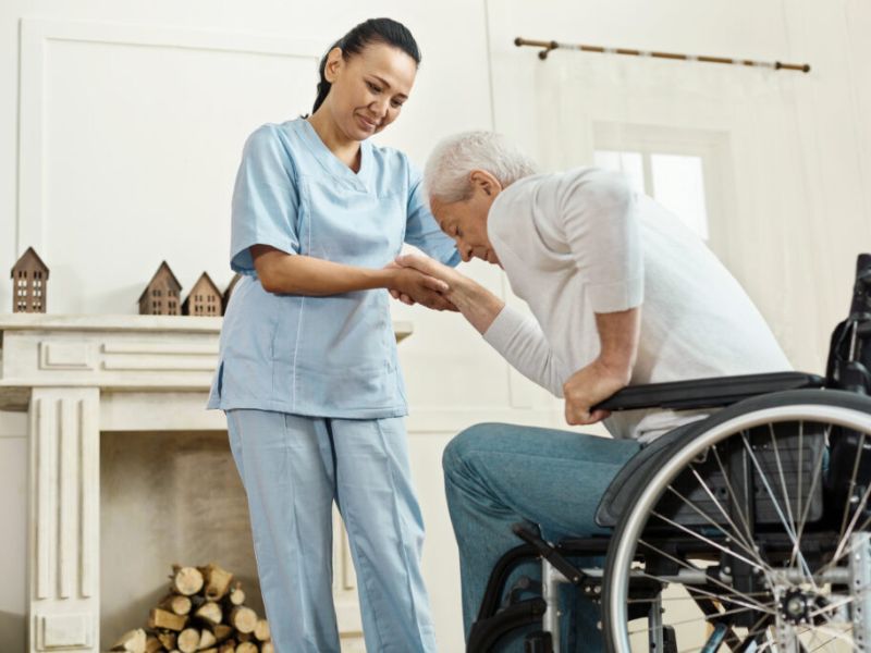 in-home caregiver assisting a senior out of a wheelchair