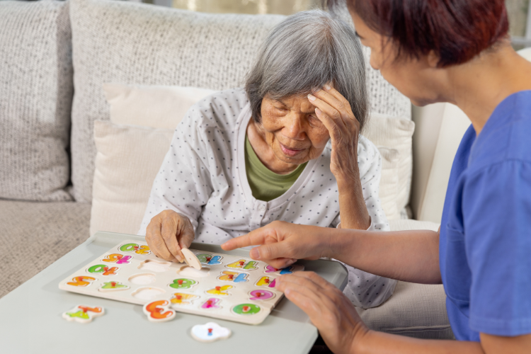 Elderly woman with Alzheimer's doing a puzzle with an in-home caregiver