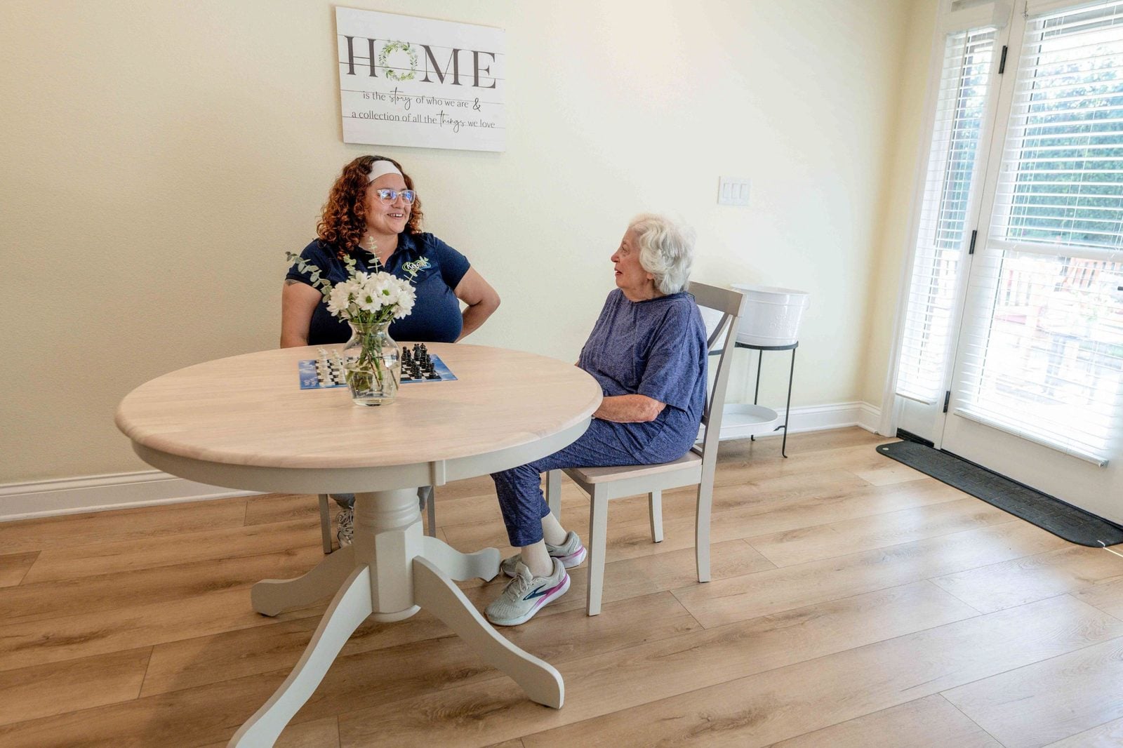 Keen caregiver talking with a resident at the dining table